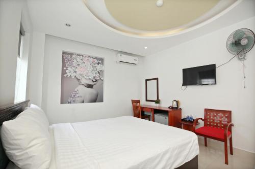 a bedroom with a bed and a desk and a tv at Pearl Sea Hotel in Danang