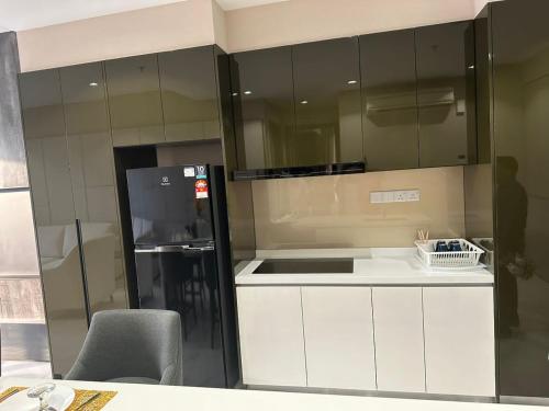 uma cozinha com armários brancos e um frigorífico preto em ASTRA @ 8 Kia Peng Suites em Kuala Lumpur