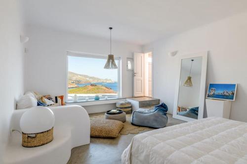 a white bedroom with a bed and a large window at Mykonos Citadel in Mikonos