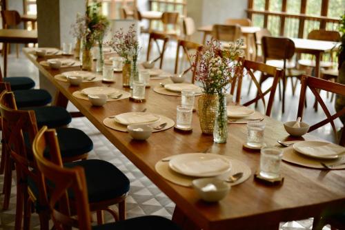 a long wooden table with chairs and plates and flowers at Proud Phu Fah Muang Chiang Mai in Chiang Mai