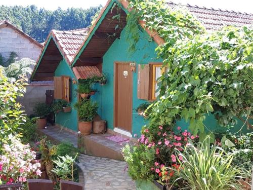 a blue house with flowers and plants at Casa Moreira´s Chalés in Monte Verde