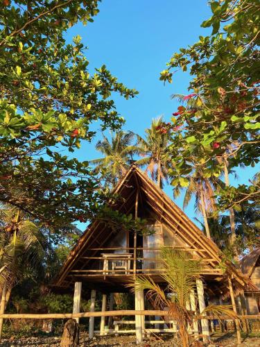 a bamboo house with palm trees in the background at Kasa Raya By The Sea in Tibiao