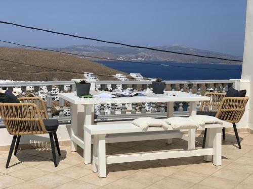 d'une table et de chaises blanches sur un balcon avec vue. dans l'établissement Gerani Deluxe Houses 2, à Astypalée