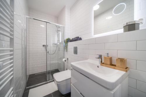 a white bathroom with a sink and a shower at Internesto Brno Vlhka 9 in Brno