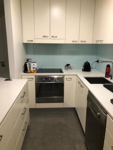 a kitchen with white cabinets and a black oven at The Heart of Glenelg in Glenelg
