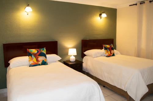 2 camas en una habitación de hotel con 2 lámparas en Inari Hostal, en Guatemala