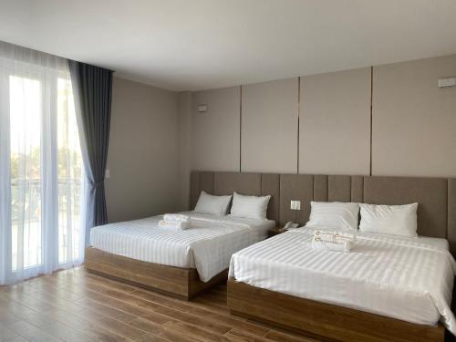 1 dormitorio con 2 camas y ventana grande en HO TRAM GOLDEN HOTEL, en Thuận Biên