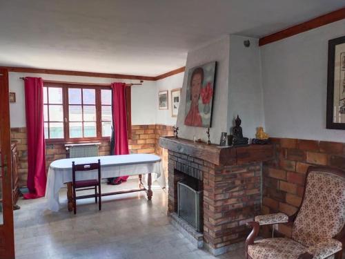 a living room with a brick fireplace and a table at Gîte La vie au vert Spacieux et autonome in Malay-le-Grand