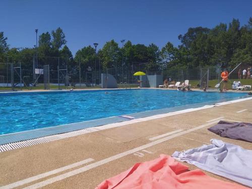a large swimming pool with people sitting around it at Agradable adosado en soto de llanera in Llanera