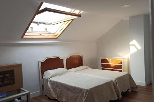 a bedroom with a large bed with a skylight at Agradable adosado en soto de llanera in Llanera