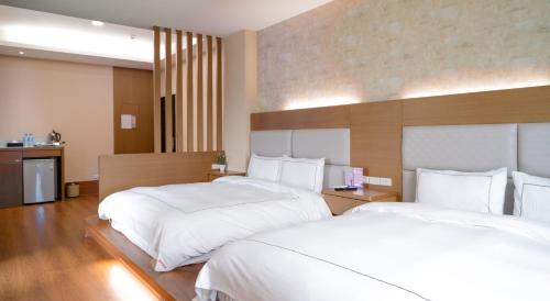 員山鄉的住宿－聽風會館，配有白色床单的酒店客房内的两张床