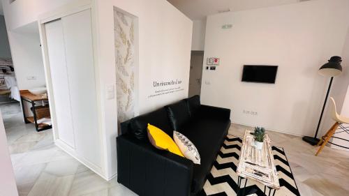a living room with a black couch and a table at Apartamentos GADIR CENTRO in Cádiz