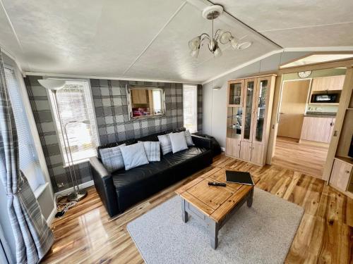 a living room with a black couch and a table at Cragside View Lodge in Newton on the Moor