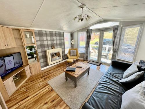 een woonkamer met een bank en een tafel bij Cragside View Lodge in Newton on the Moor