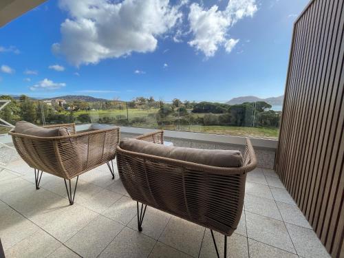 a balcony with two chairs and a large window at Golden Tulip Porto-Vecchio in Porto-Vecchio