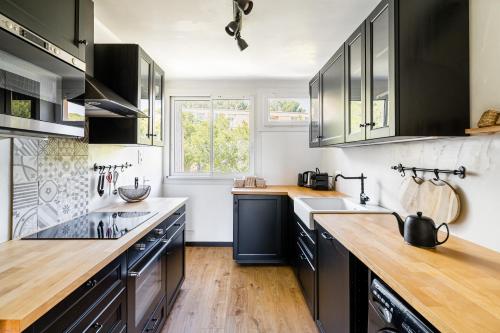 - une cuisine avec des armoires noires et du parquet dans l'établissement Le Bosquet 3 par Dodo-a-Cassis, à Cassis