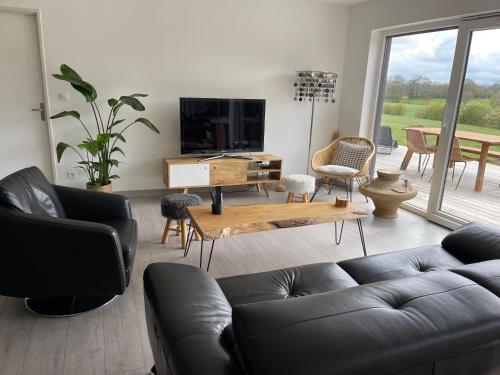 salon z kanapą i telewizorem w obiekcie Maison de charme vue d'exception w mieście Étreham
