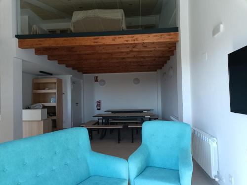 - un salon avec deux chaises bleues et une table dans l'établissement Albergue El Muro, 