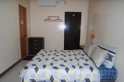 a bedroom with a bed and a dresser in it at Yoo C Apartment in Dumaguete