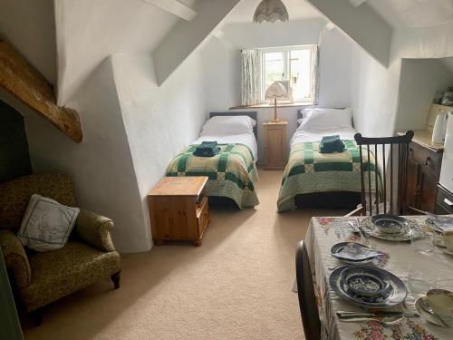 a attic room with two beds and a chair at Corndonford farm in Newton Abbot