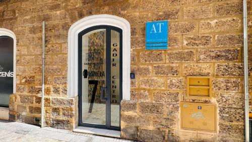 a brick building with a door and a sign on it at Apartamentos GADIR CENTRO in Cádiz