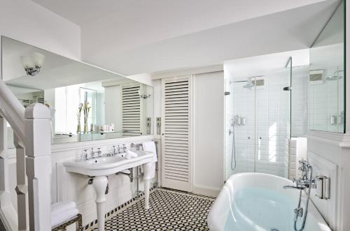La salle de bains blanche est pourvue d'un lavabo et d'une baignoire. dans l'établissement Château Hôtel Grand Barrail, à Saint-Émilion