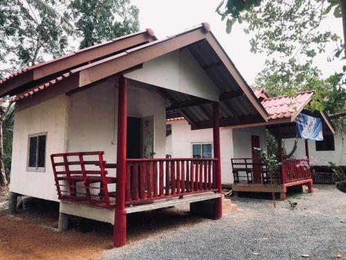 uma pequena casa branca com um alpendre e duas cadeiras em Garden Home, Chanthaburi em Ban Bo