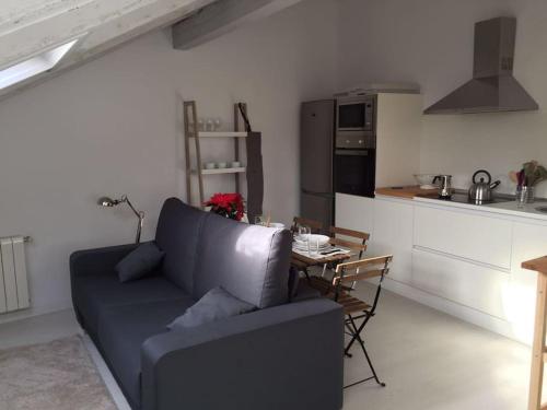 ein Wohnzimmer mit einem Sofa und einem Tisch in der Küche in der Unterkunft New and bright Puertochico attic in Santander