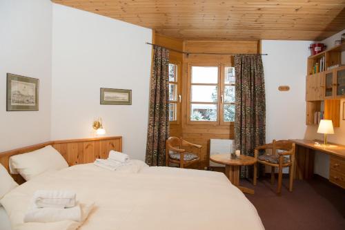 Schlafzimmer mit einem Bett, einem Schreibtisch und einem Fenster in der Unterkunft Ferienwohnung Schweizerhof 604 Lenzerheide in Lenzerheide