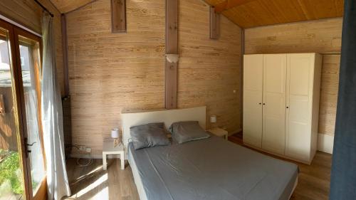 um quarto com uma cama num chalé de madeira em Calme - détente - proche lac em Biscarrosse