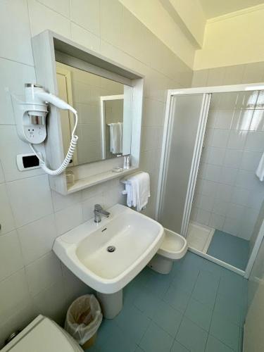 a bathroom with a sink and a toilet and a mirror at Hotel Corallo in Fano