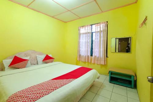 1 dormitorio con 1 cama con almohadas rojas y blancas en OYO 92503 Penginapan & Villa Sirait, en Parapat
