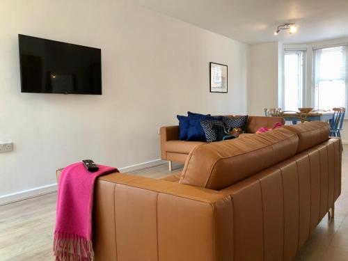 uma sala de estar com um sofá castanho e uma televisão em House with parking, short stroll to Quay, shops and restaurants em Poole