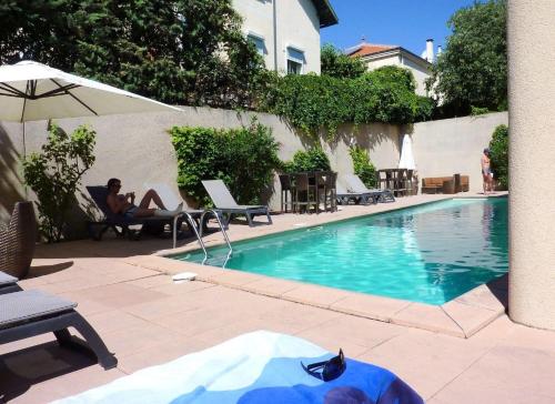 a man sitting in a chair next to a swimming pool at Ma place au sud Aix Parking in Aix-en-Provence