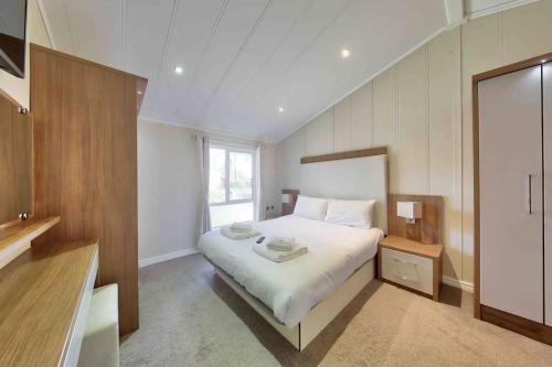 1 dormitorio con cama blanca y ventana en New Forest lodge - 194 NO PETS en Fordingbridge