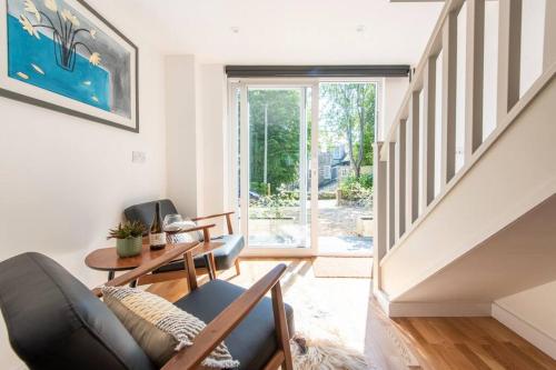 a living room with a couch and a stair case at The Studio, Rosebud. 5 minutes walk to beach. in Uny Lelant