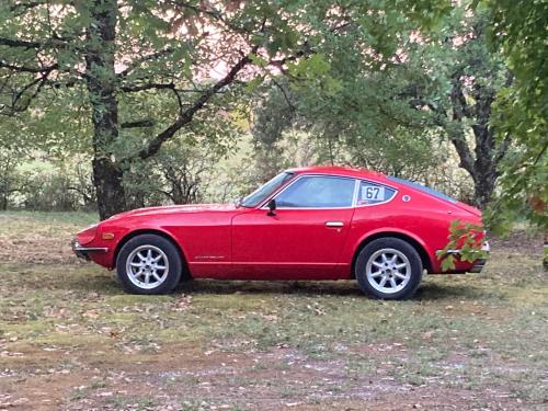 a red car is parked in a field at Le Murmure des Fées in Issigeac