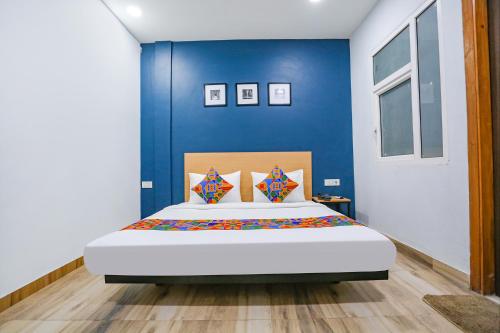 een slaapkamer met een groot bed met een blauwe muur bij FabHotel F9 Peeragarhi in New Delhi