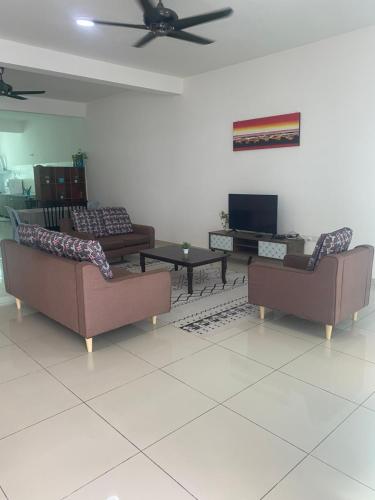 a living room with three couches and a tv at FangFei Homestay in Seremban