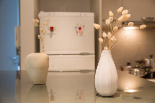 three white vases sitting on a counter with flowers in them at Lovely New Βuild Flat Near Metro - Free Parking in Athens