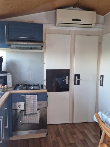 uma pequena cozinha com um fogão e uma porta em Mazet d El gato em Arles