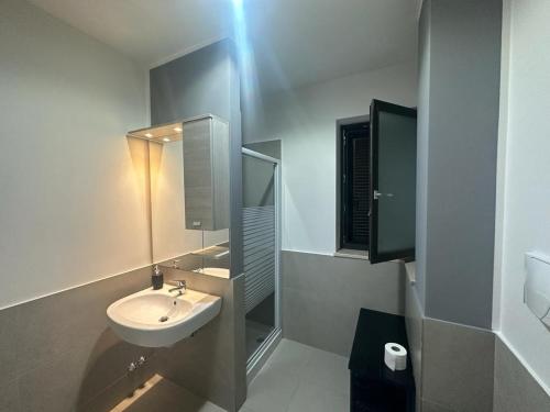a white bathroom with a sink and a mirror at Villa swamy in Bisceglie