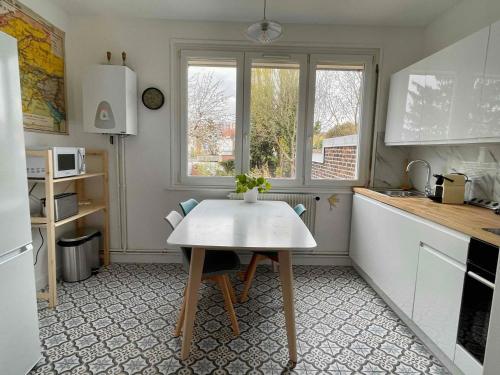 uma pequena cozinha com uma mesa e uma janela em La chambre jaune maison avec grande terrasse et garage privé em Lille
