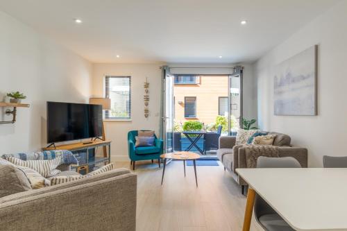 a living room with couches and a flat screen tv at 1 Putsborough - Luxury Apartment at Byron Woolacombe, only 4 minute walk to Woolacombe Beach! in Woolacombe