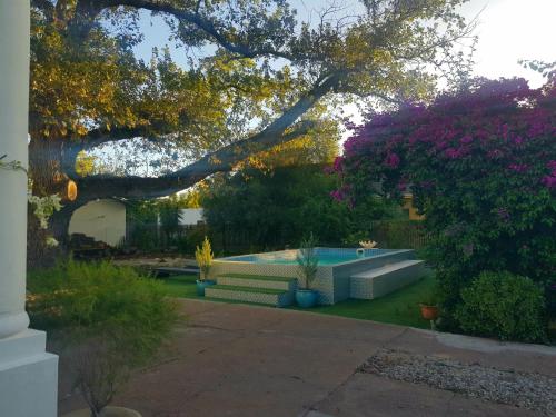 a backyard with a pool and a tree and flowers at The Heritage country house in Porterville