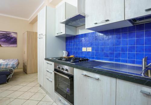 a kitchen with a stove and blue tiles on the wall at A due passi dal Mare in Riomaggiore