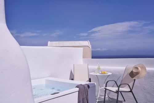 a bathroom with a tub and a table and chairs at Fava Eco Suites in Oia