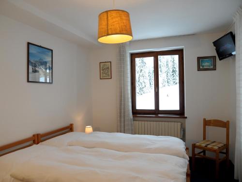 a bedroom with a white bed and a window at Hotel Pensione Dolomiti in Falcade