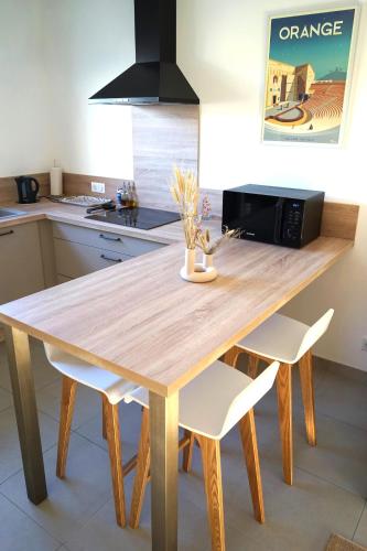 - une table en bois dans une cuisine avec des chaises blanches dans l'établissement Maison chaleureuse en Provence, à Piolenc