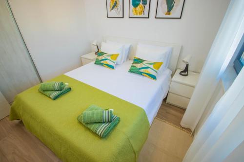 a bedroom with a bed with green sheets and pillows at Apartmani LE-LU in Kaštela